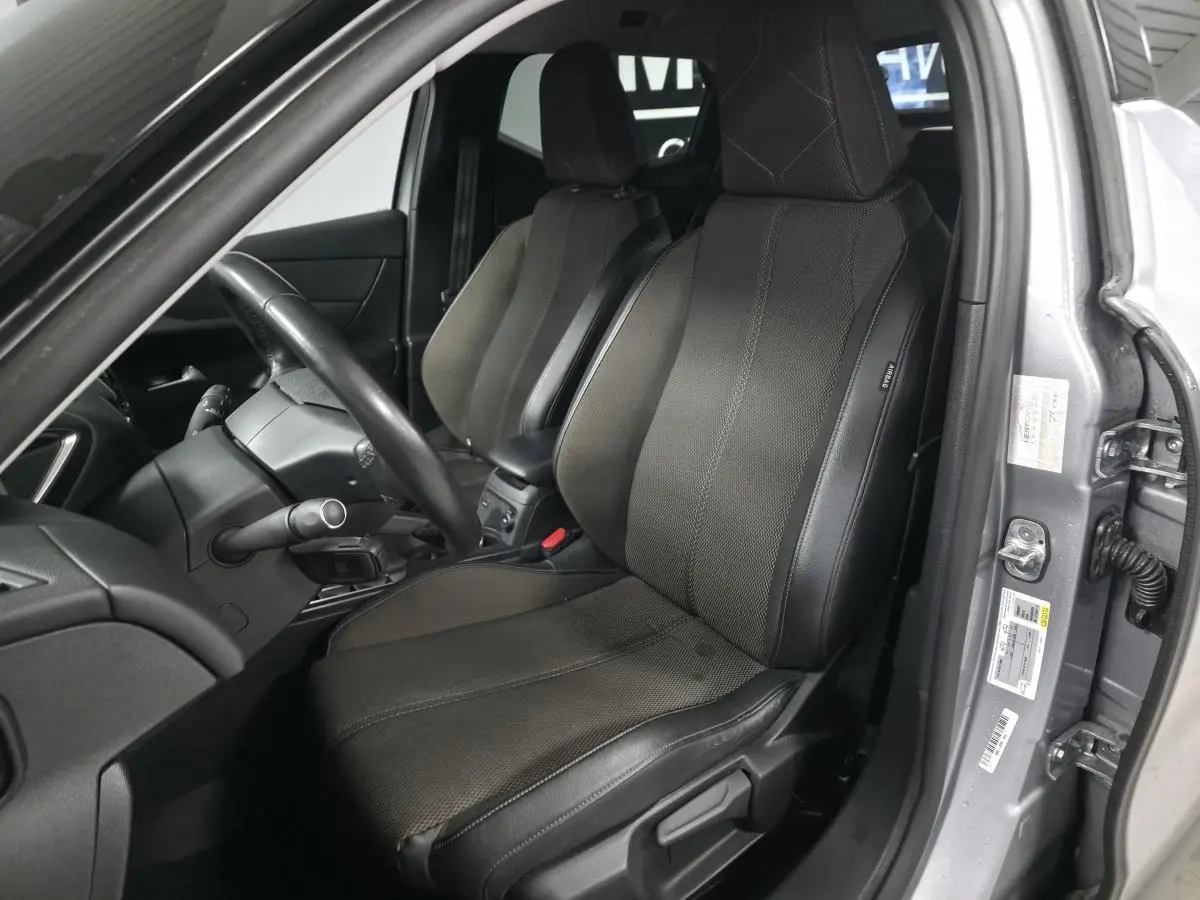 Vue intérieure côté conducteur du DS3 Crossback gris, mettant en valeur le siège avant en tissu Perruzi Bronze et le volant cuir.