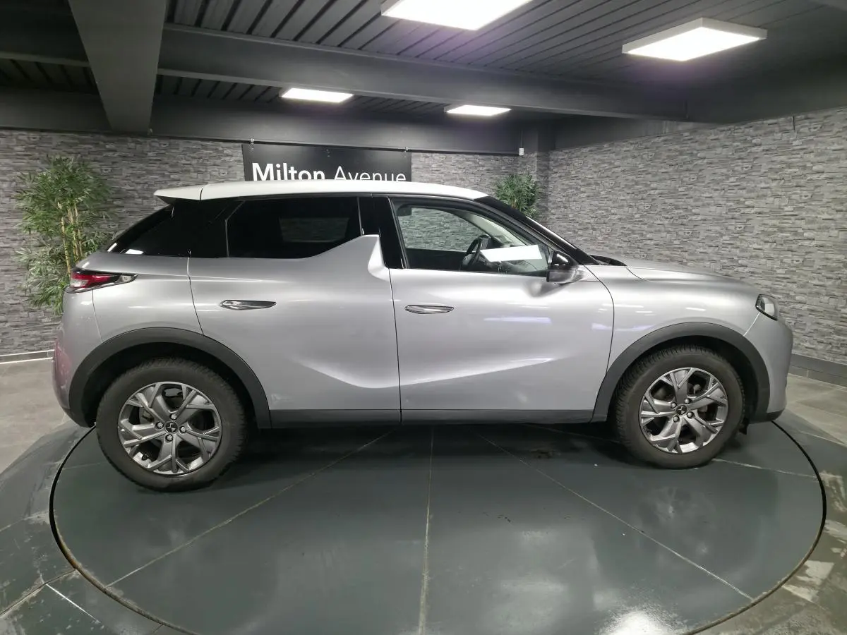 Vue de profil droit du DS3 Crossback gris métallisé avec toit blanc, jantes alliage et poignées affleurantes.