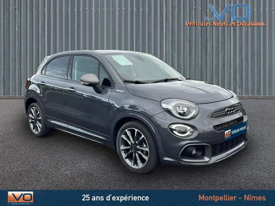 Vue 3/4 avant d'une FIAT 500X Sport gris métallisé avec jantes alliage 18 pouces sur fond urbain.