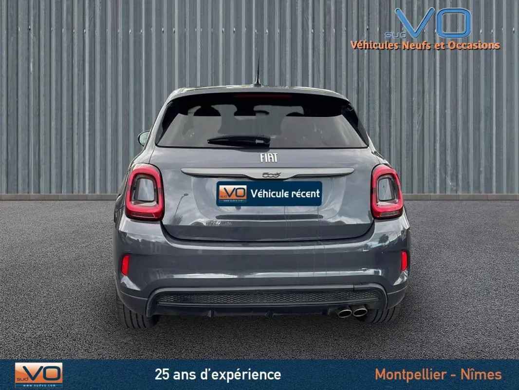 Vue arrière d'une FIAT 500X MY22 gris métallisé avec feux LED et double sortie d'échappement visible sur fond urbain.