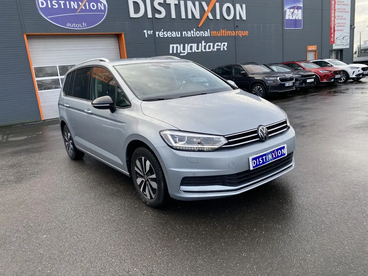 Volkswagen Touran 2025 Oyster Argent métallisé, vue 3/4 avant avec projecteurs IQ.Light et jantes distinctives.