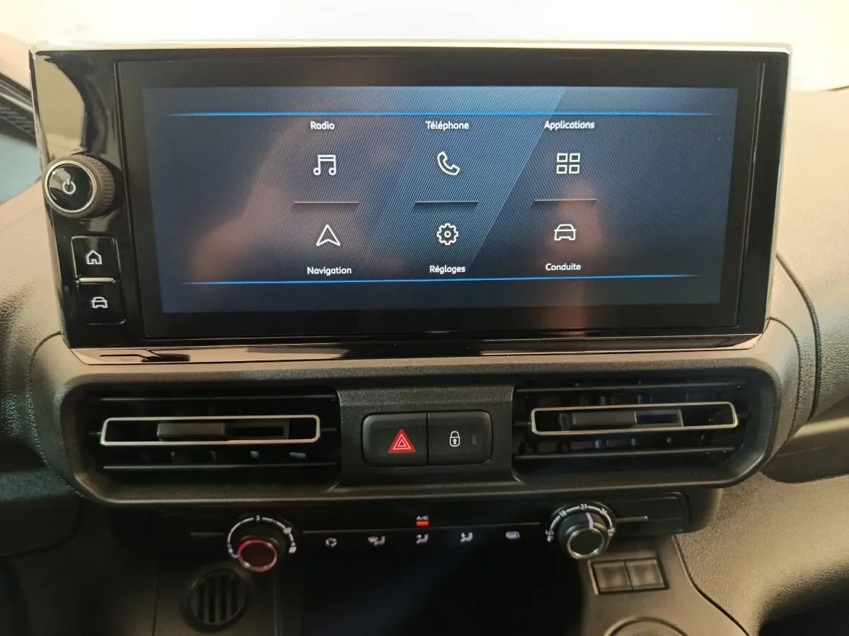 Vue rapprochée de l'écran tactile central et des commandes de climatisation du Peugeot Partner blanc 2026.