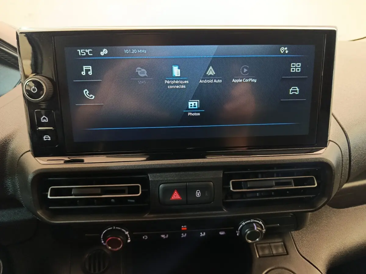 Vue rapprochée de l’écran tactile central du tableau de bord du Peugeot Partner blanc 2026 avec commandes climatisation et alertes visibles.