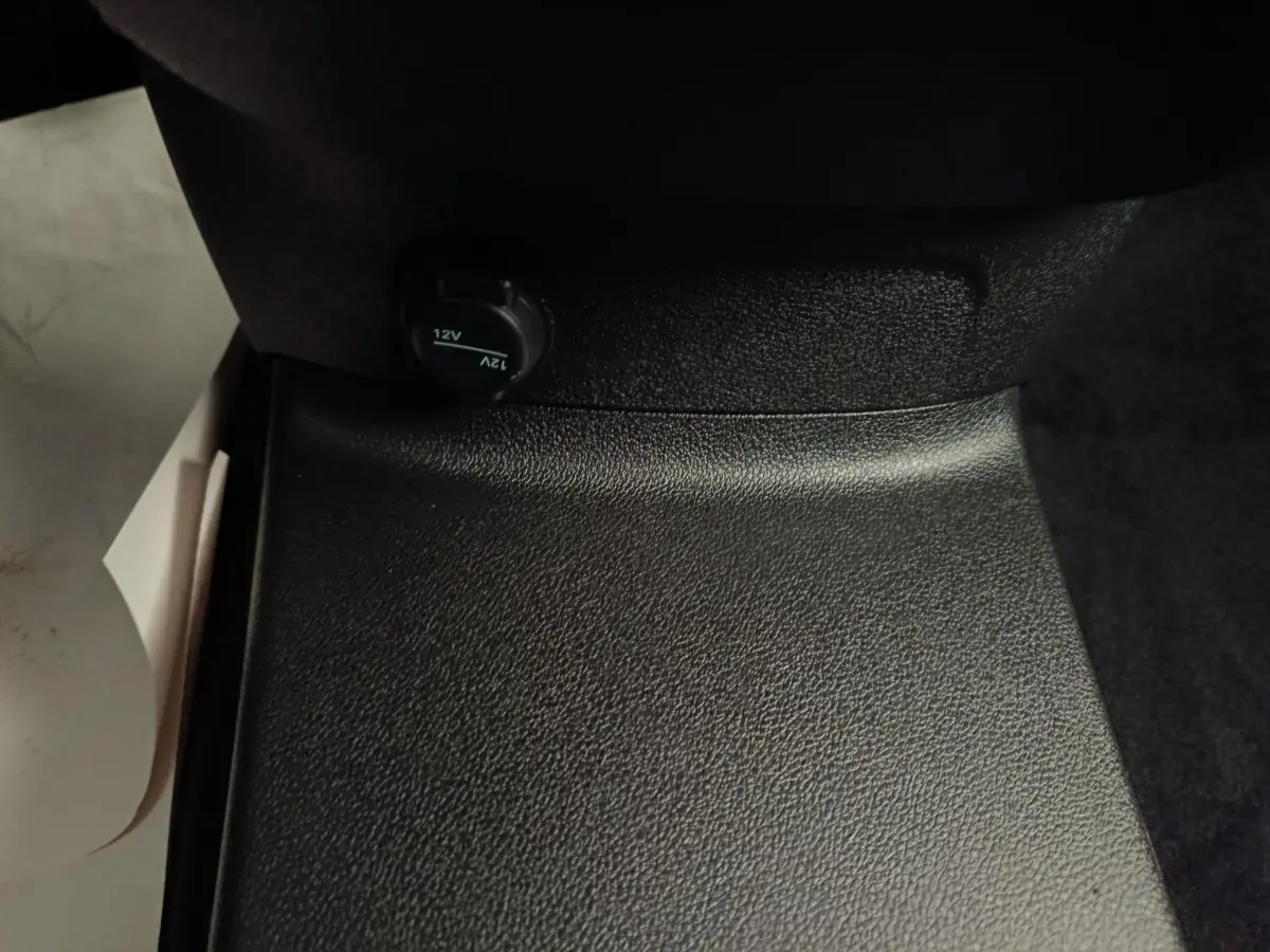 Prise 12V noire en gros plan sur la console centrale intérieure du Peugeot Partner blanc, version 2026.