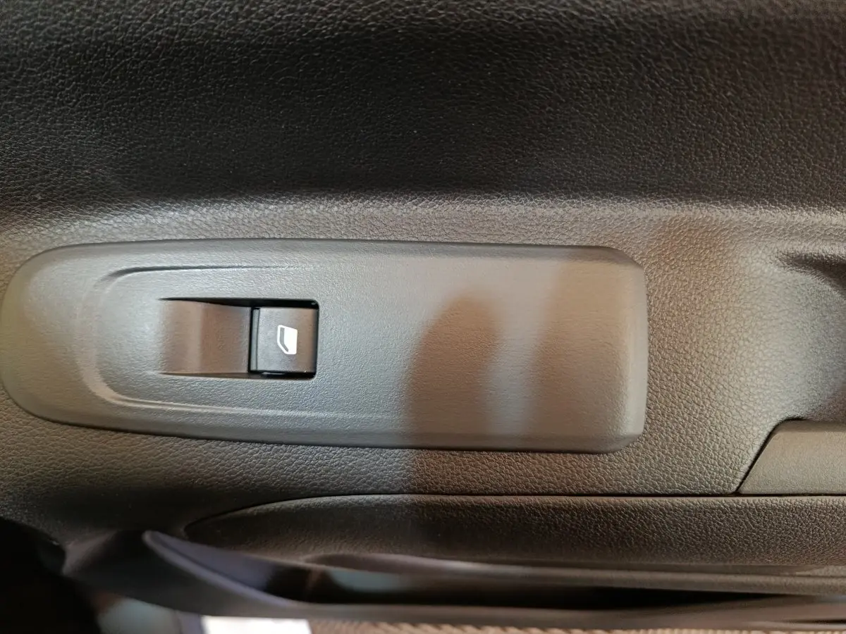 Gros plan sur l'interrupteur de lève-vitre côté conducteur du Peugeot Partner blanc, intérieur noir texturé.