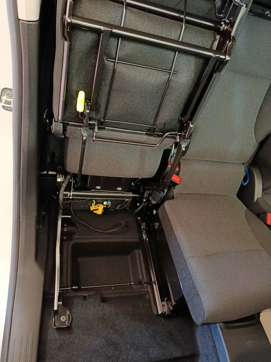 Vue intérieure en plongée du siège avant droit relevé du Peugeot Partner blanc, montrant la structure métallique et le rangement sous siège.