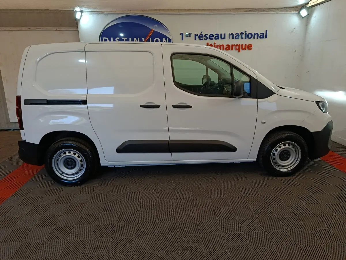 Vue de profil côté droit du Peugeot Partner blanc 2026 avec porte latérale coulissante et protections noires.