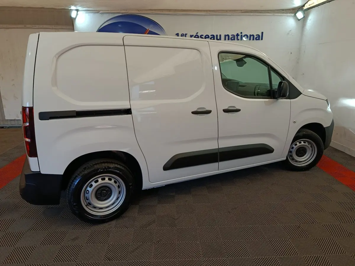 Vue de profil côté droit d’un utilitaire Peugeot Partner blanc, avec portes latérales pleines et jantes acier simples.
