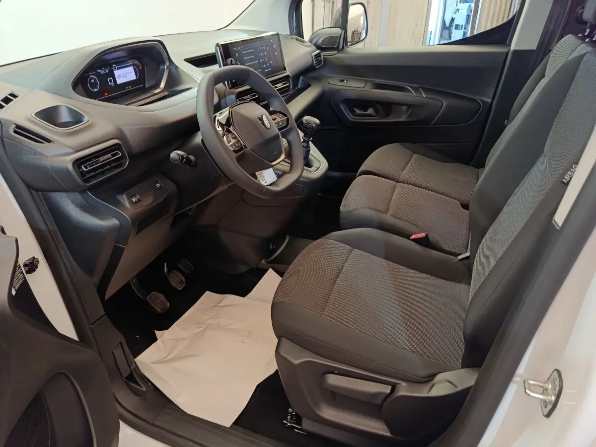 Intérieur avant droit du Peugeot Partner 2026 blanc, montrant tableau de bord numérique et sièges tissu gris.