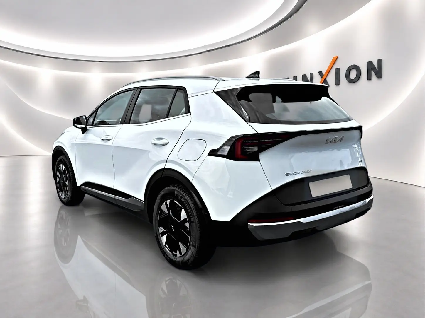 KIA Sportage 1.6 hybride blanc vu en 3/4 arrière droit, avec jantes alu noires et feux arrière LED.