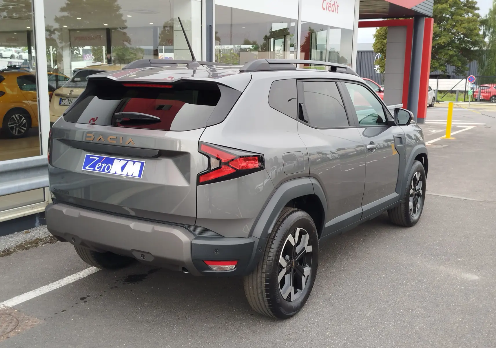 Vue 3/4 arrière droite du Dacia Duster gris schiste 2025 avec feux arrière LED et jantes noires distinctives.