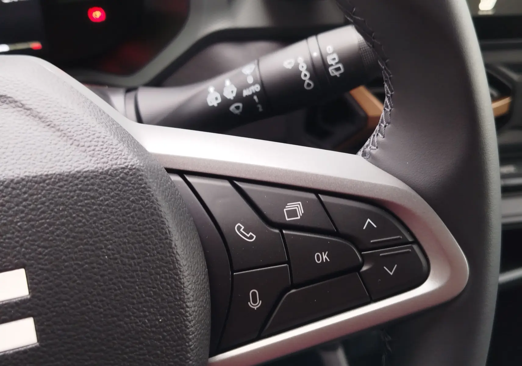 Gros plan sur les commandes multifonctions noires et argentées du volant du Dacia Duster 2025, intérieur gris.