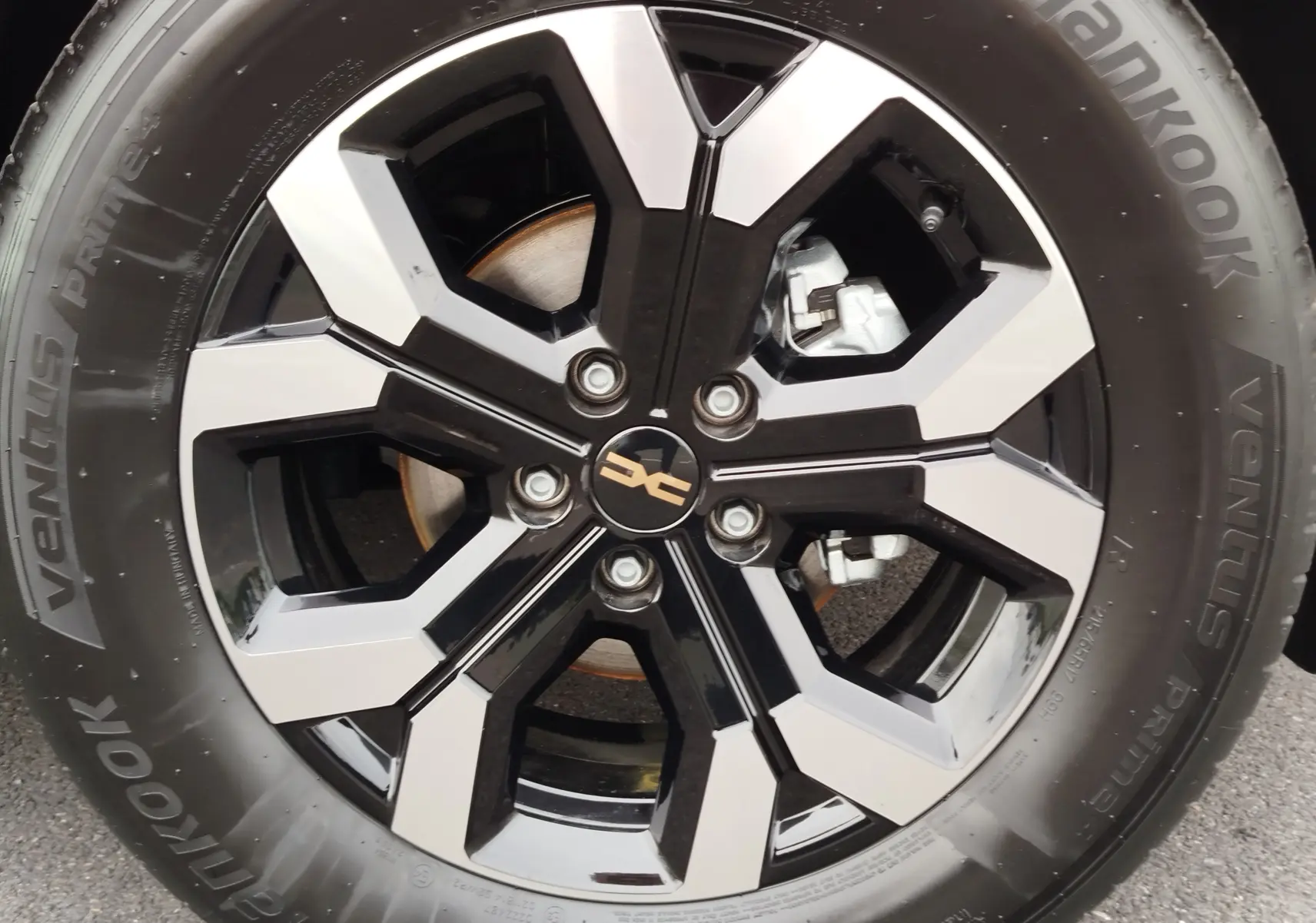 Gros plan sur la jante noire et argentée du Dacia Duster gris schiste avec logo central et pneu Hankook visible.