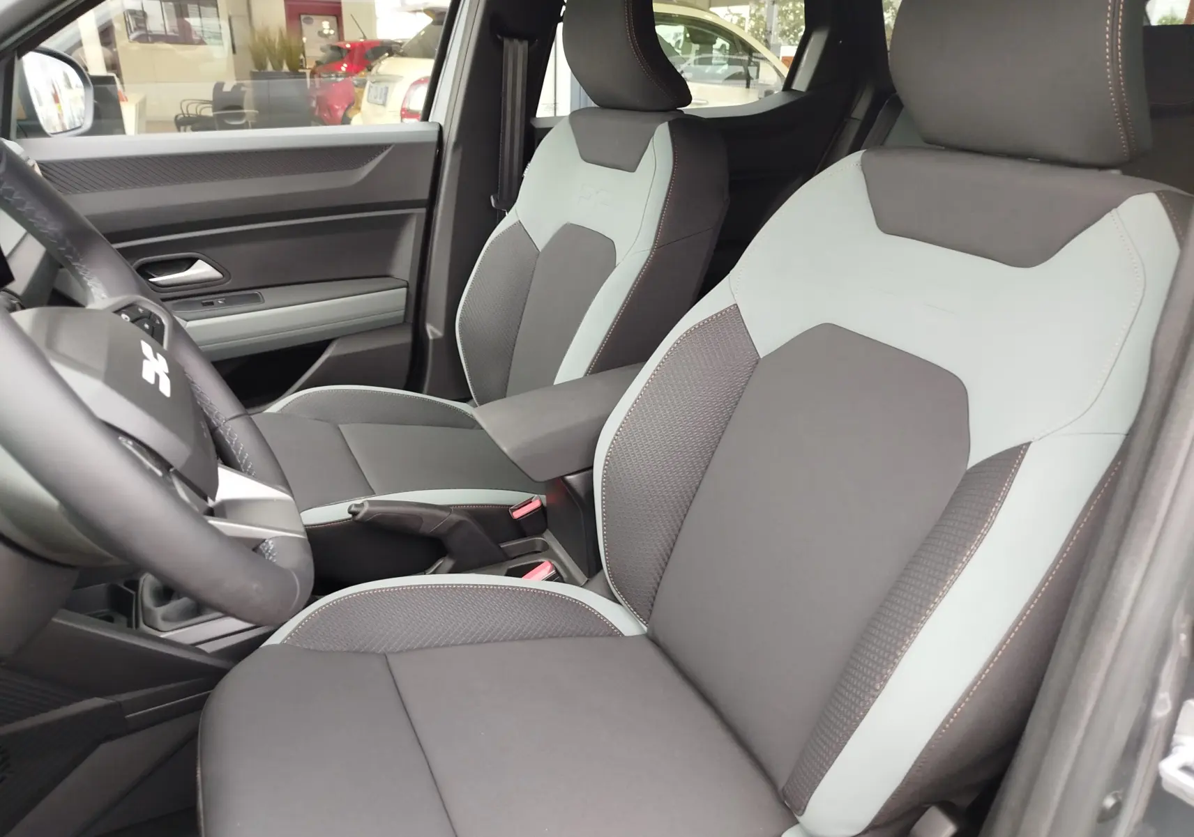 Vue intérieure du Dacia Duster 2025 montrant les sièges avant bicolores gris clair et foncé avec surpiqûres contrastées.