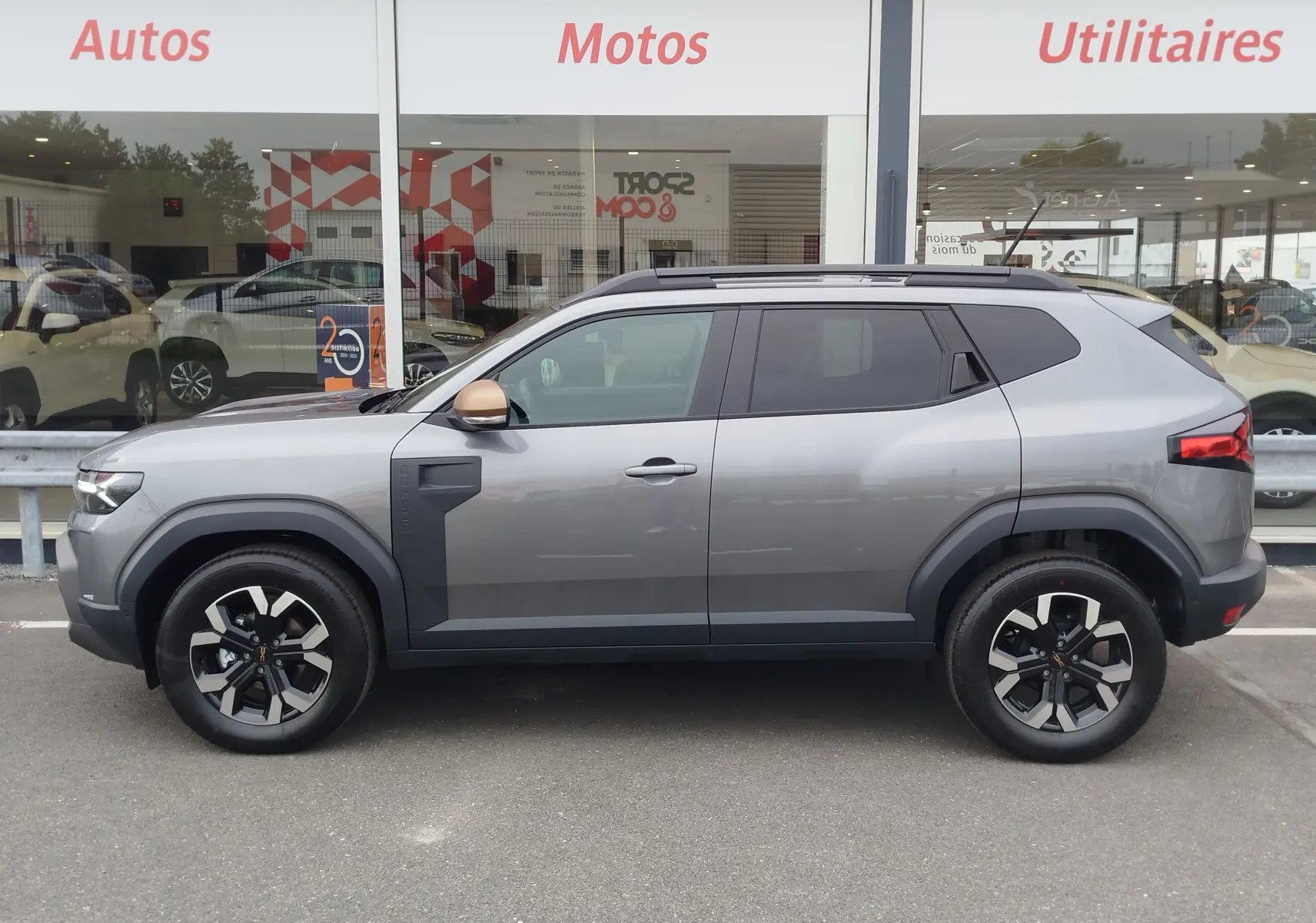 Profil côté gauche du Dacia Duster gris schiste 2025 avec jantes noires et détails noirs contrastants.