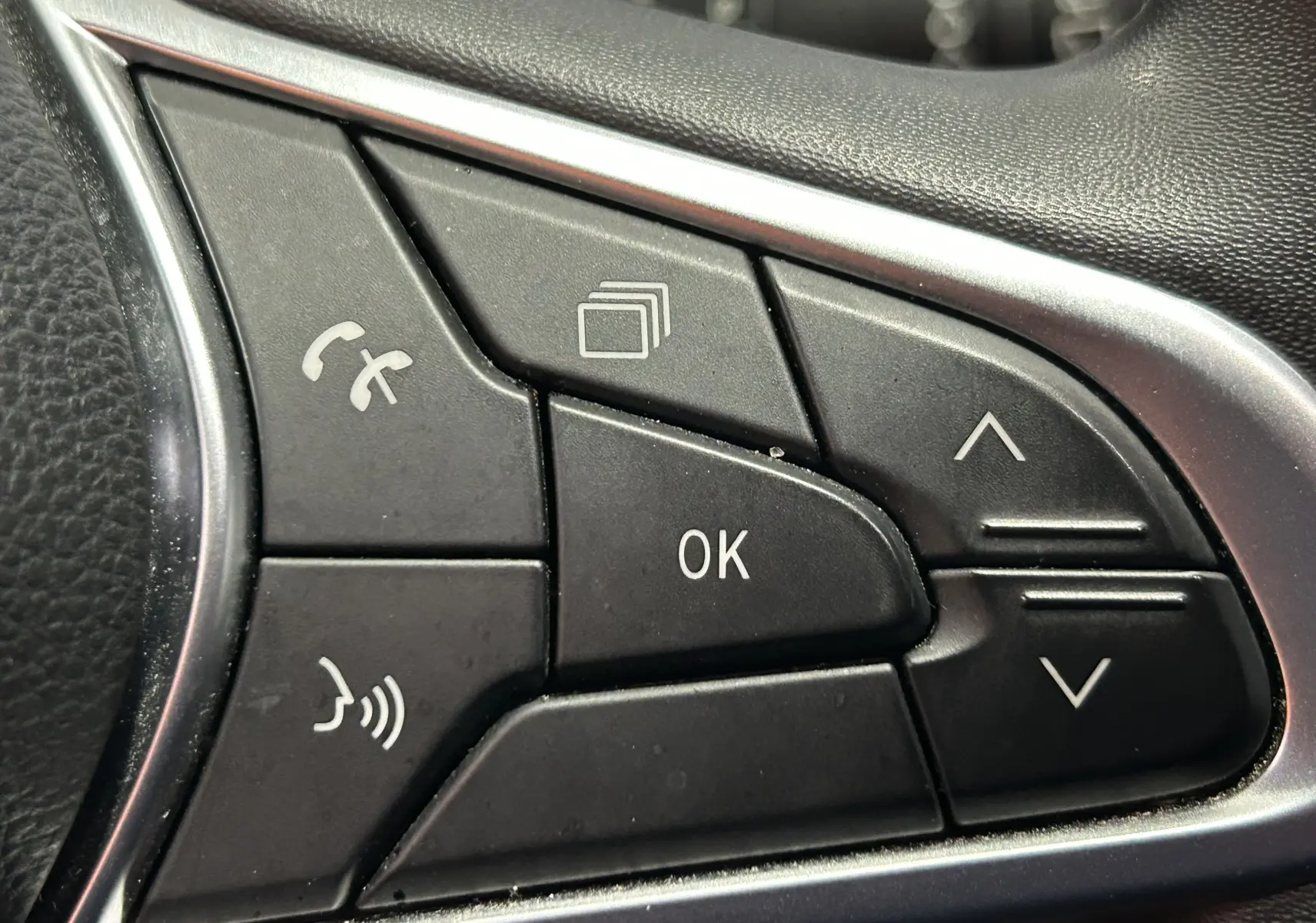 Gros plan sur les commandes au volant noir de la Renault Clio V TCe 90 TECHNO 2023, avec boutons multifonctions et cadre argenté.