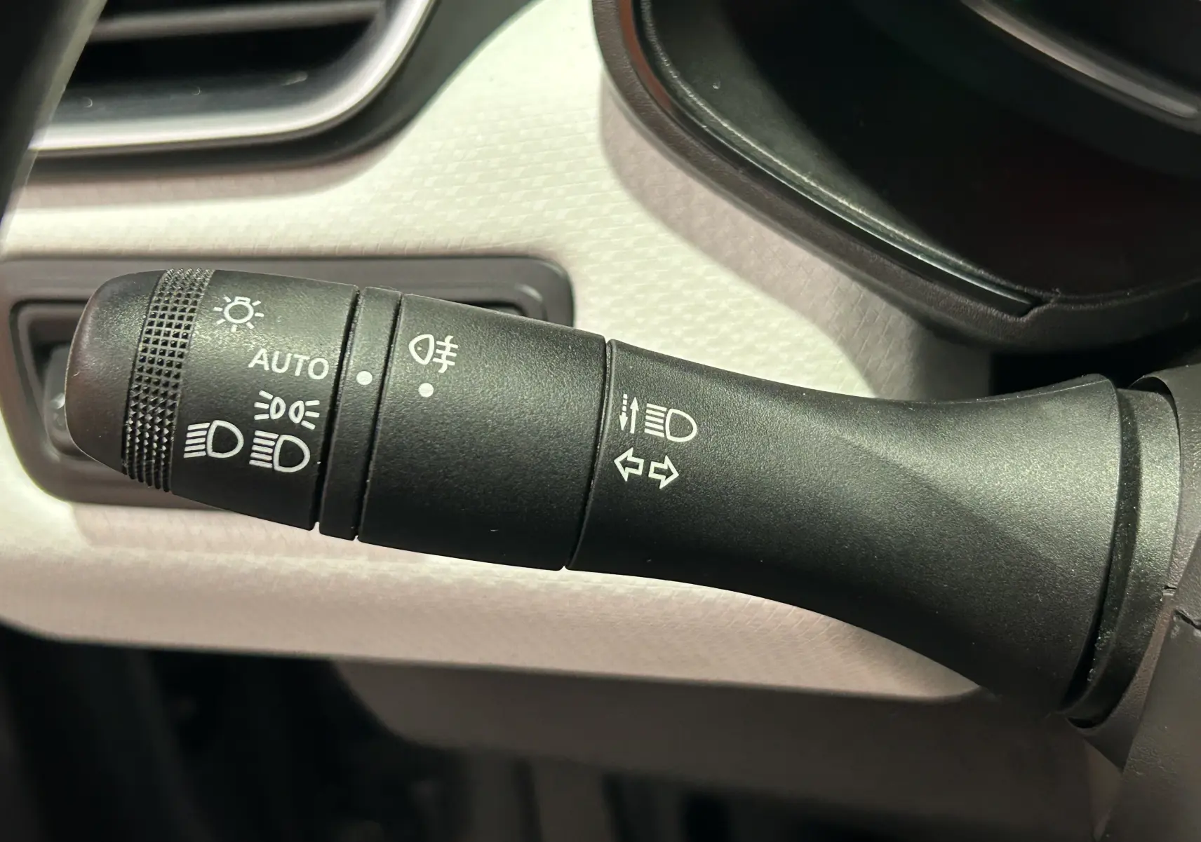 Gros plan sur la commande des feux et clignotants dans l'habitacle gris clair d'une Renault Clio V TCe 90 TECHNO 2023.