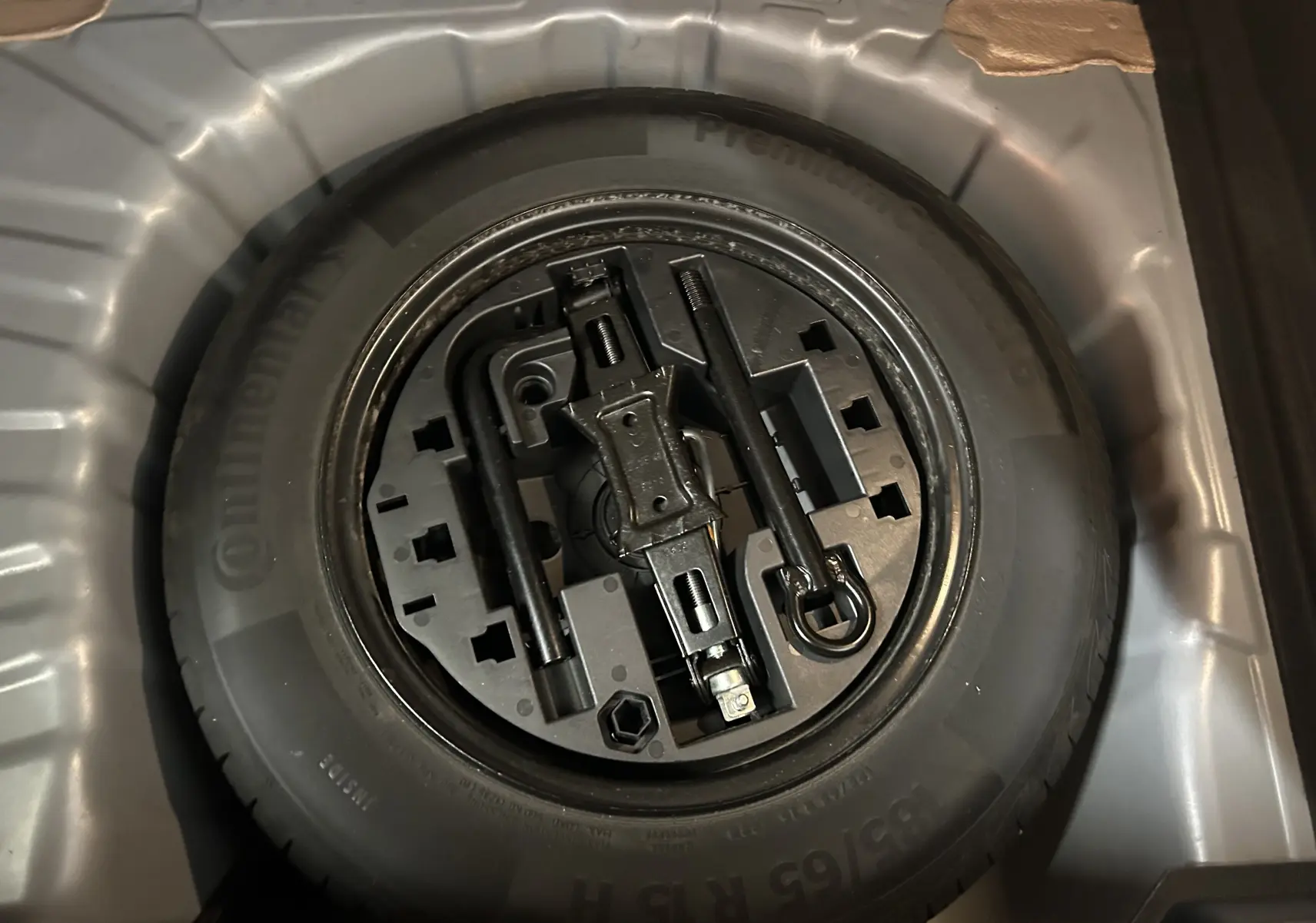 Roue de secours avec outils de changement dans le coffre d'une Renault Clio V gris 2023.