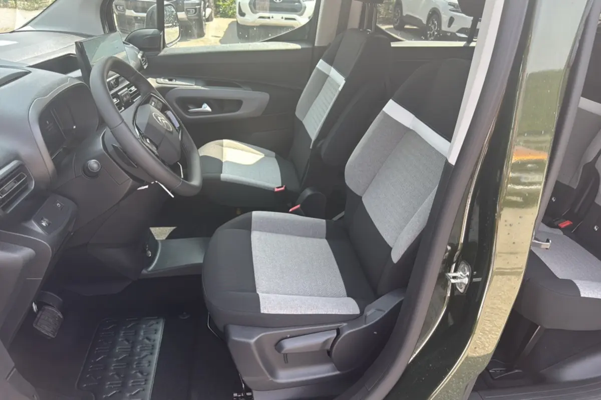 Vue intérieure côté conducteur du Citroën Berlingo 2025 Sirkka green, sièges tissu gris et noir avec volant cuir multifonctions.