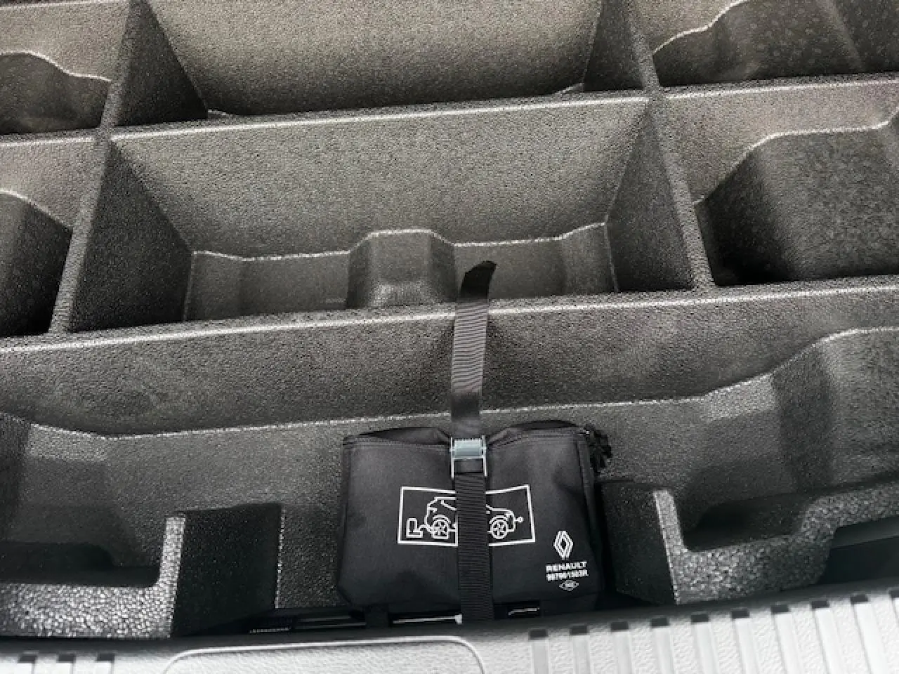 Rangement de coffre noir étoilé avec trousse d'urgence Renault attachée par sangle.