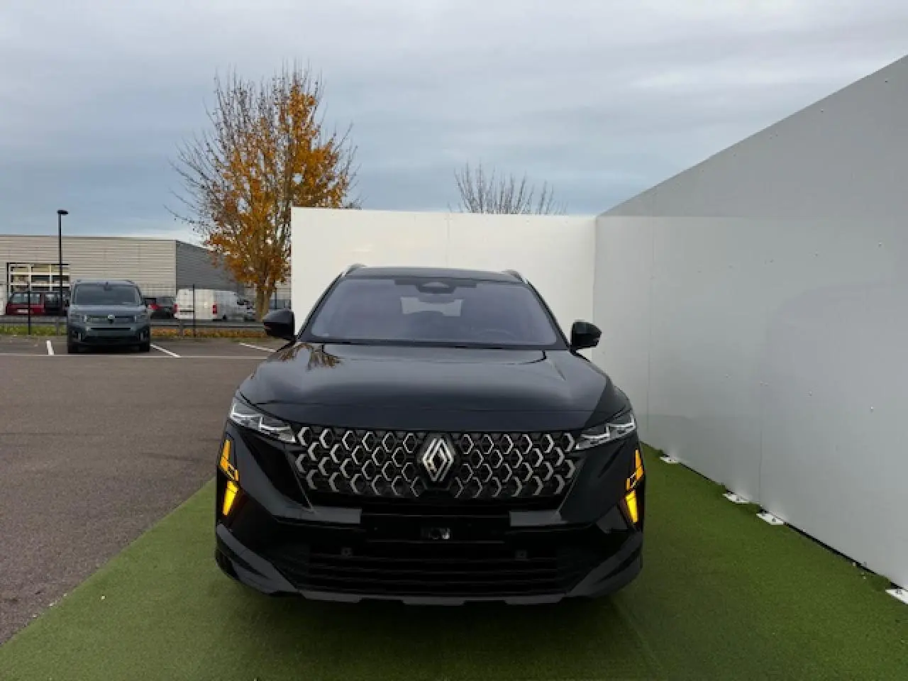 Vue de face d'un Renault Espace VI noir étoilé avec calandre gris chrome satin et feux LED allumés.