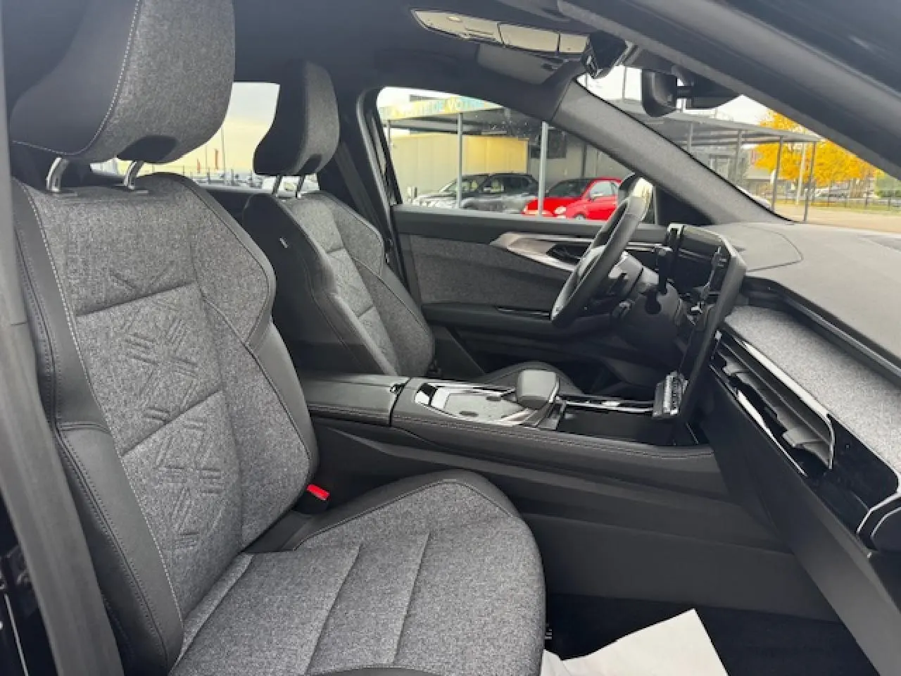 Vue intérieure côté conducteur du Renault Espace VI 1.2 Full Hybrid 2025 avec sièges textile gris et console centrale noire.