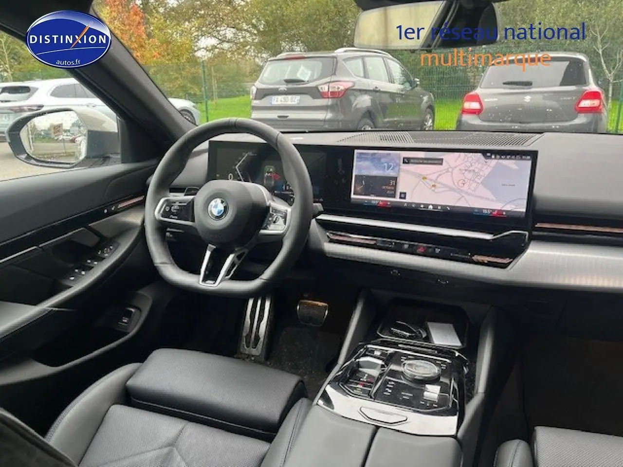 Vue intérieure avant de la BMW Série 5 gris, avec tableau de bord numérique et large écran tactile GPS.