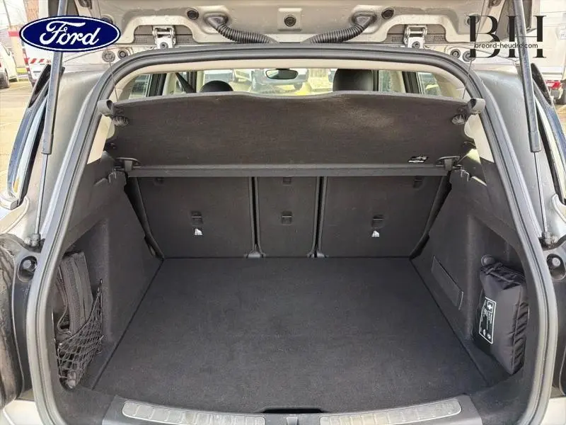 Coffre ouvert vu de l'arrière d'une MINI COUNTRYMAN Melting Silver III, espace de chargement avec cache-bagages noir.