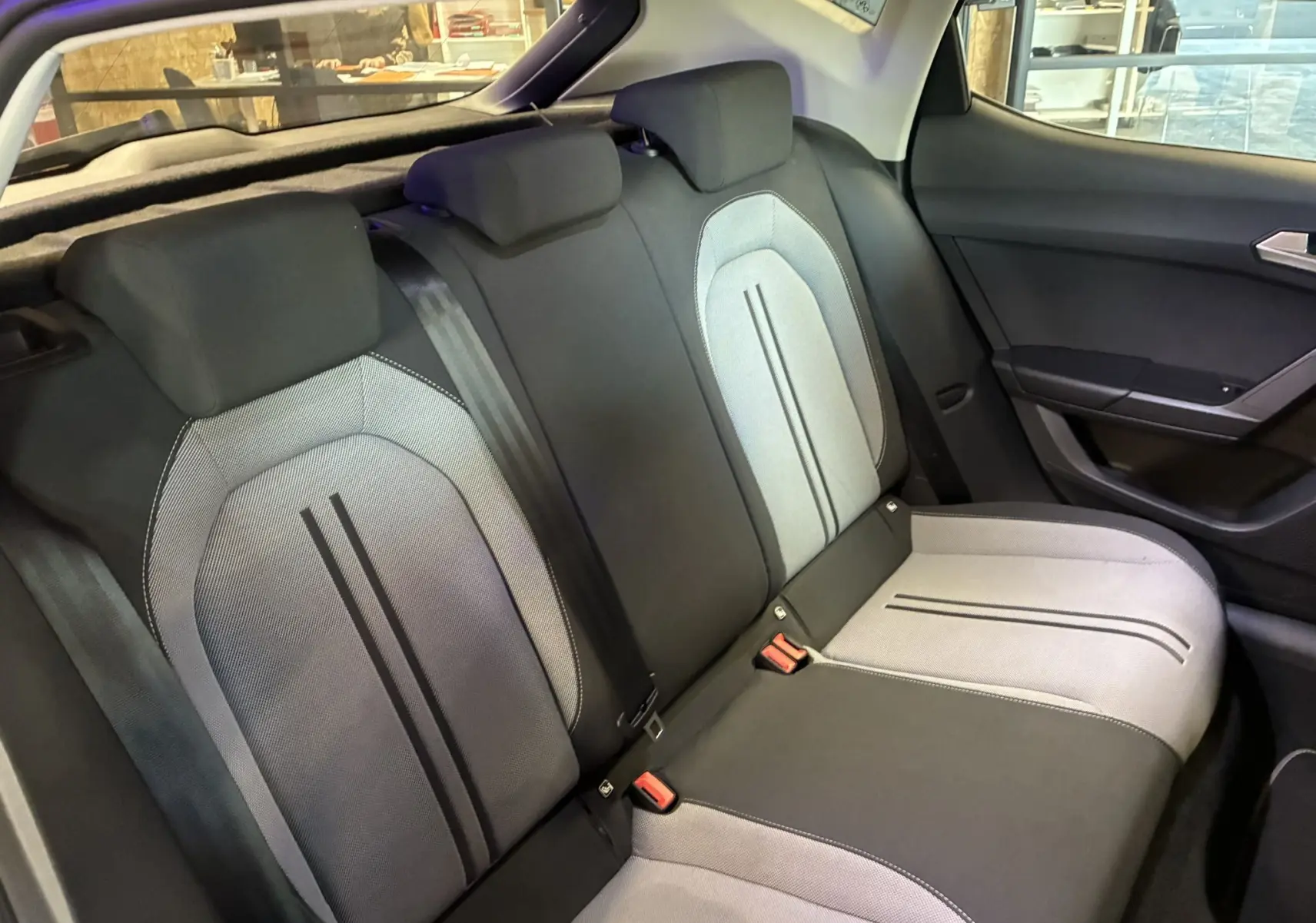 Vue intérieure des sièges arrière en tissu noir et gris de la SEAT LEON 2021, avec ceintures de sécurité visibles.