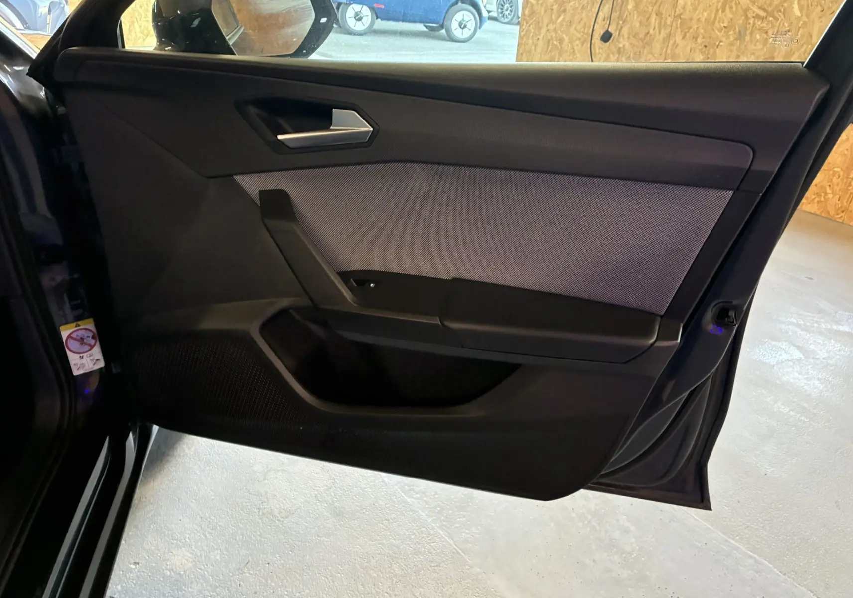 Vue intérieure côté gauche de la porte avant d'une SEAT LEON gris 2021, avec habillage tissu noir et détails modernes.