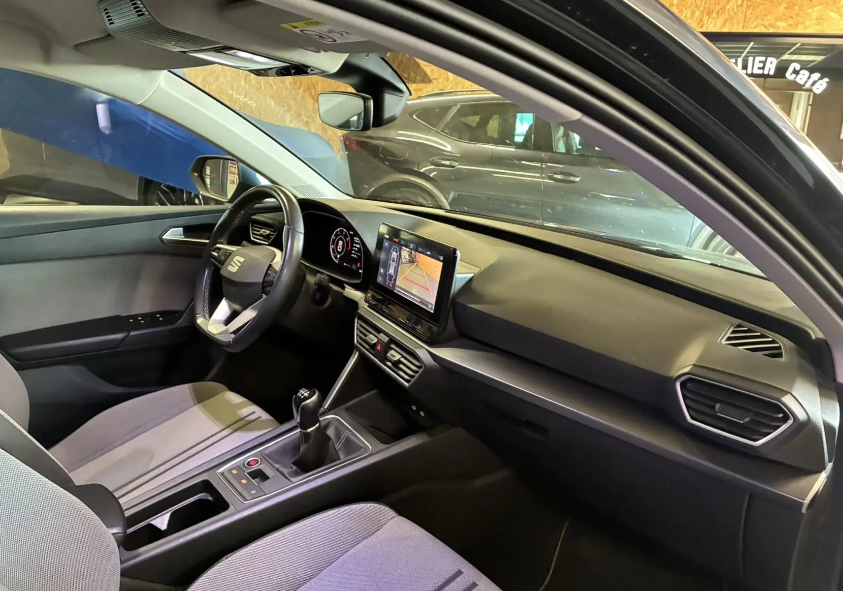 Vue intérieure côté conducteur de la SEAT Leon gris 2021, avec tableau de bord moderne et écran tactile central.