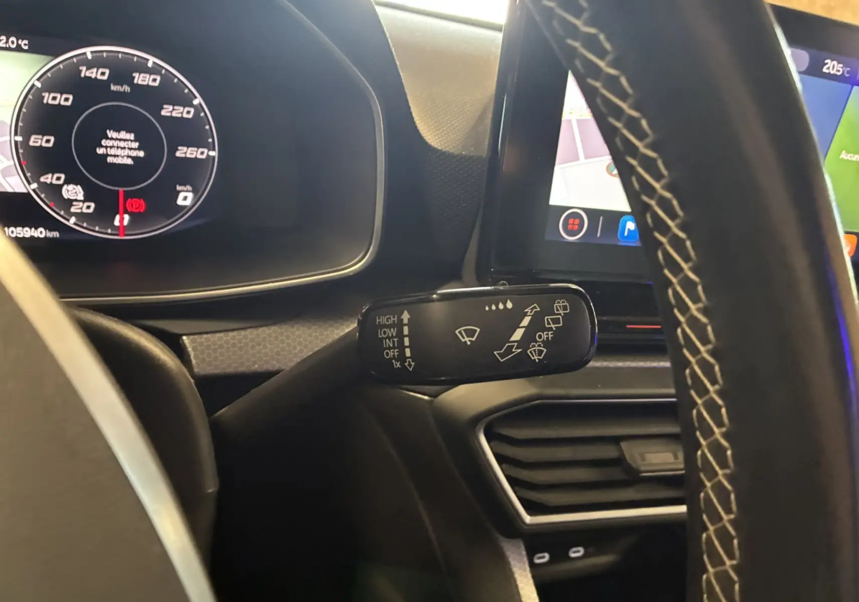 Gros plan sur le commodo d’essuie-glace côté gauche du tableau de bord d’une SEAT Leon gris 2021, volant avec surpiqûres blanches.