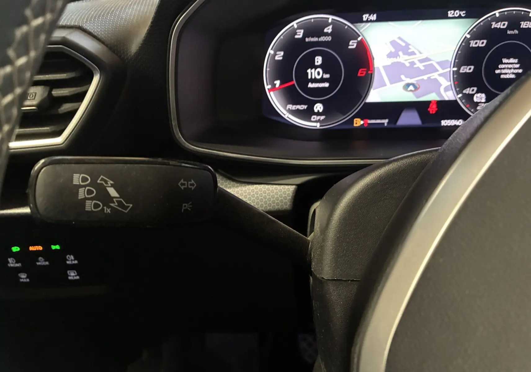 Gros plan sur le combiné d'instruments digital et le commodo gauche du volant dans l'habitacle noir du SEAT Leon gris 2021.