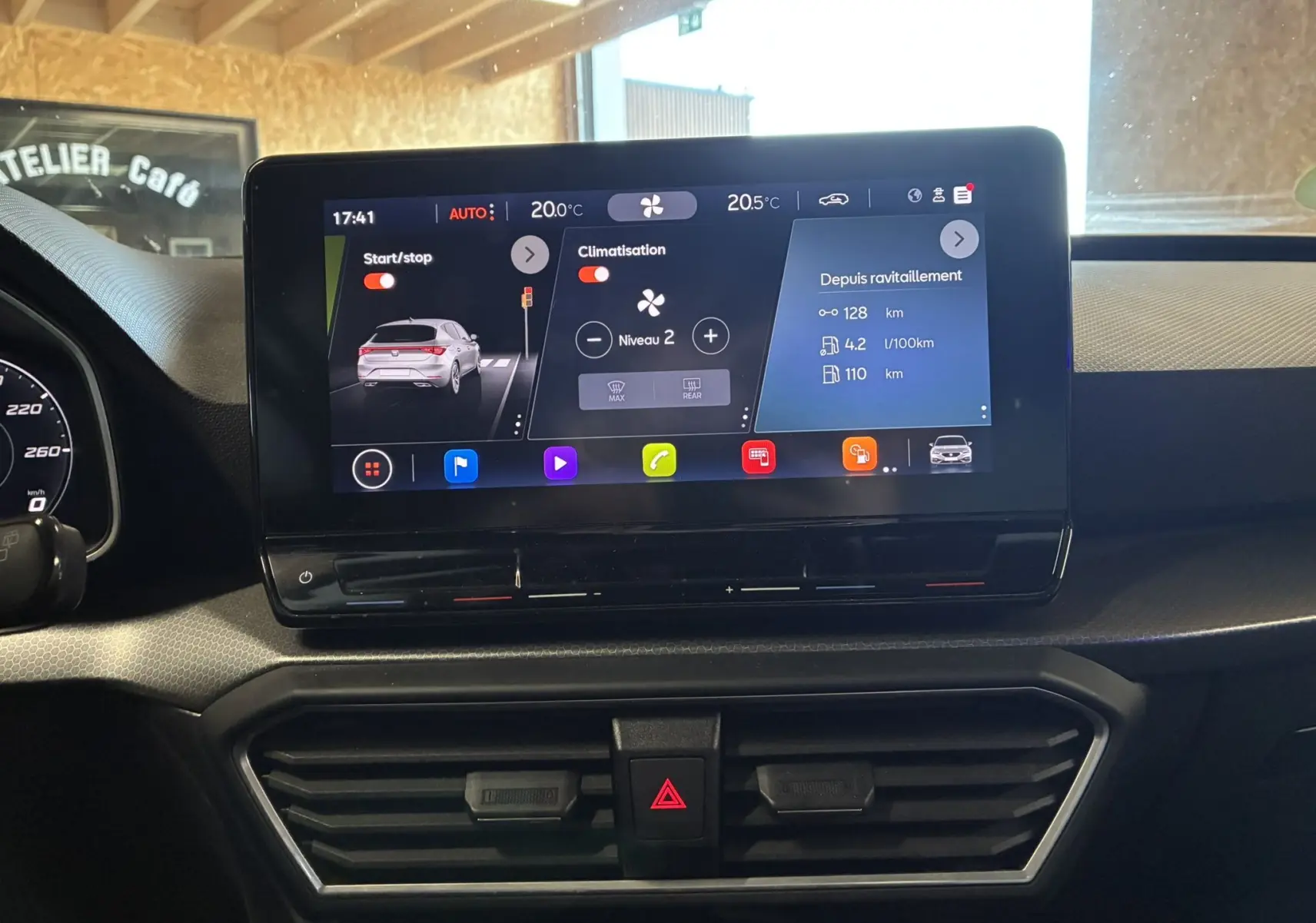 Écran tactile central du tableau de bord d’une SEAT Leon 2.0 TDI gris, affichant la climatisation et l’info consommation.