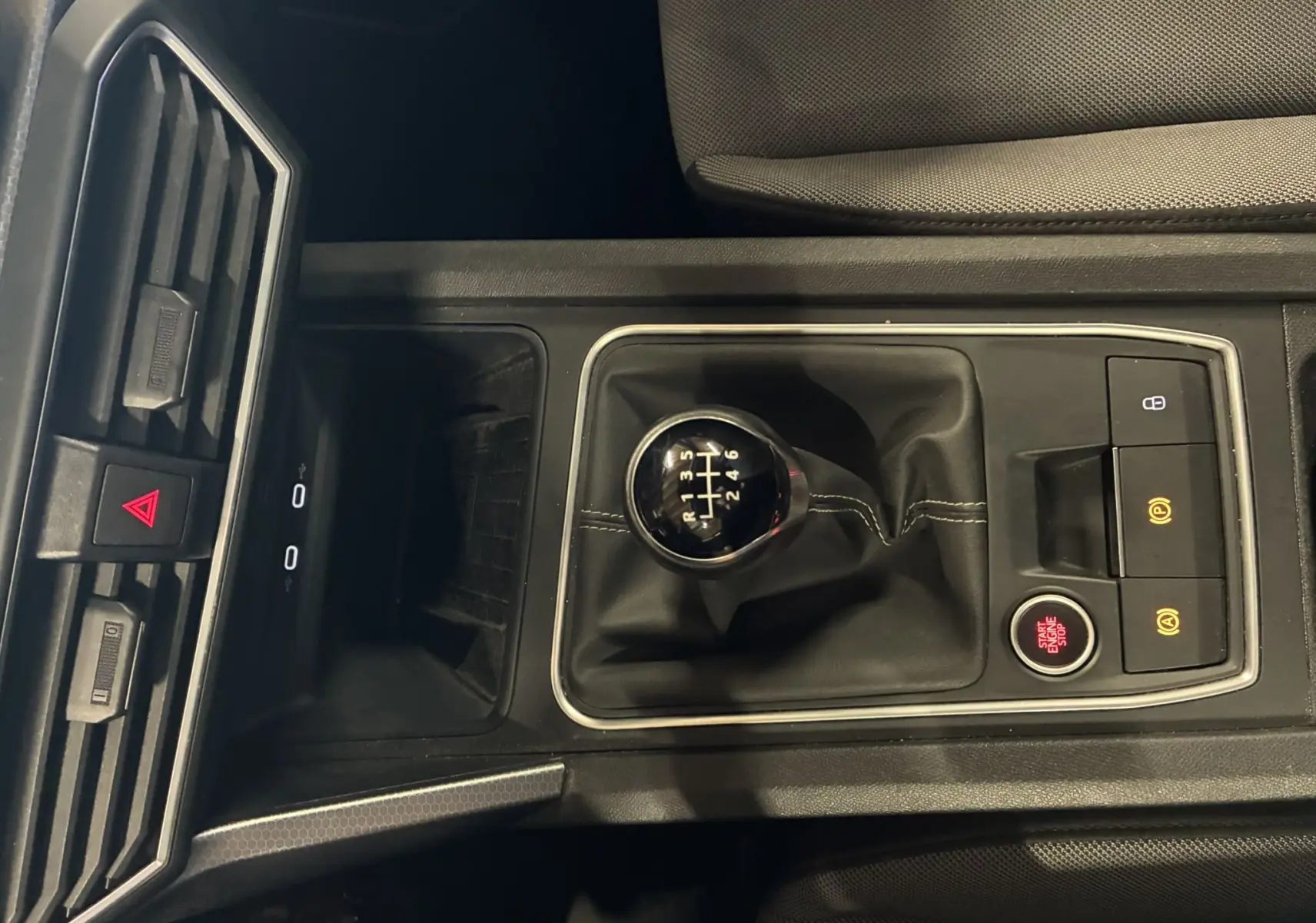 Vue rapprochée de la console centrale gris foncé du SEAT LEON 2.0 TDI 115 STYLE avec levier de vitesse manuel et boutons de contrôle.