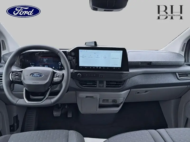 Vue intérieure frontale du tableau de bord gris clair du Ford Transit Custom Fourgon avec écran tactile central et volant multifonctions.