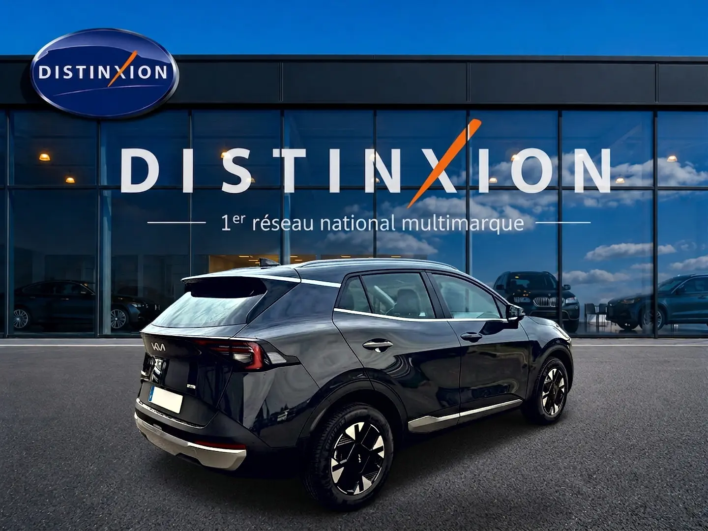 Vue 3/4 arrière droite d'un KIA Sportage gris eclipse 2026 avec jantes alu et feux arrière LED, devant un showroom Distinxion.