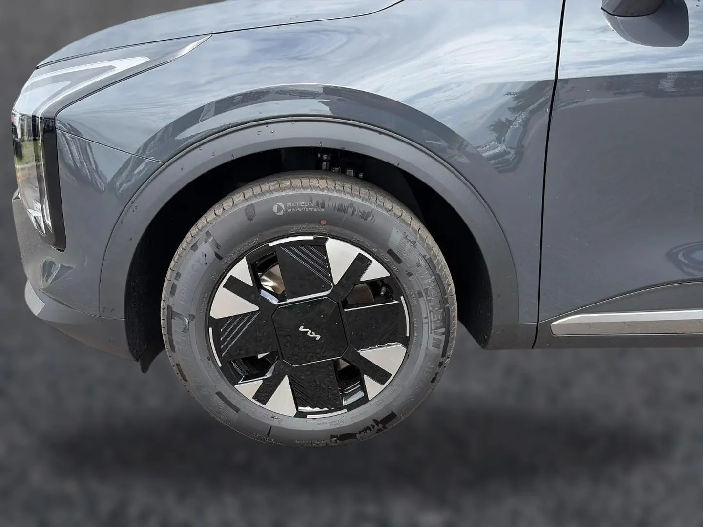 Gros plan sur la roue avant gauche du KIA SPORTAGE gris eclipse, avec jante alu noire et argentée au design moderne.