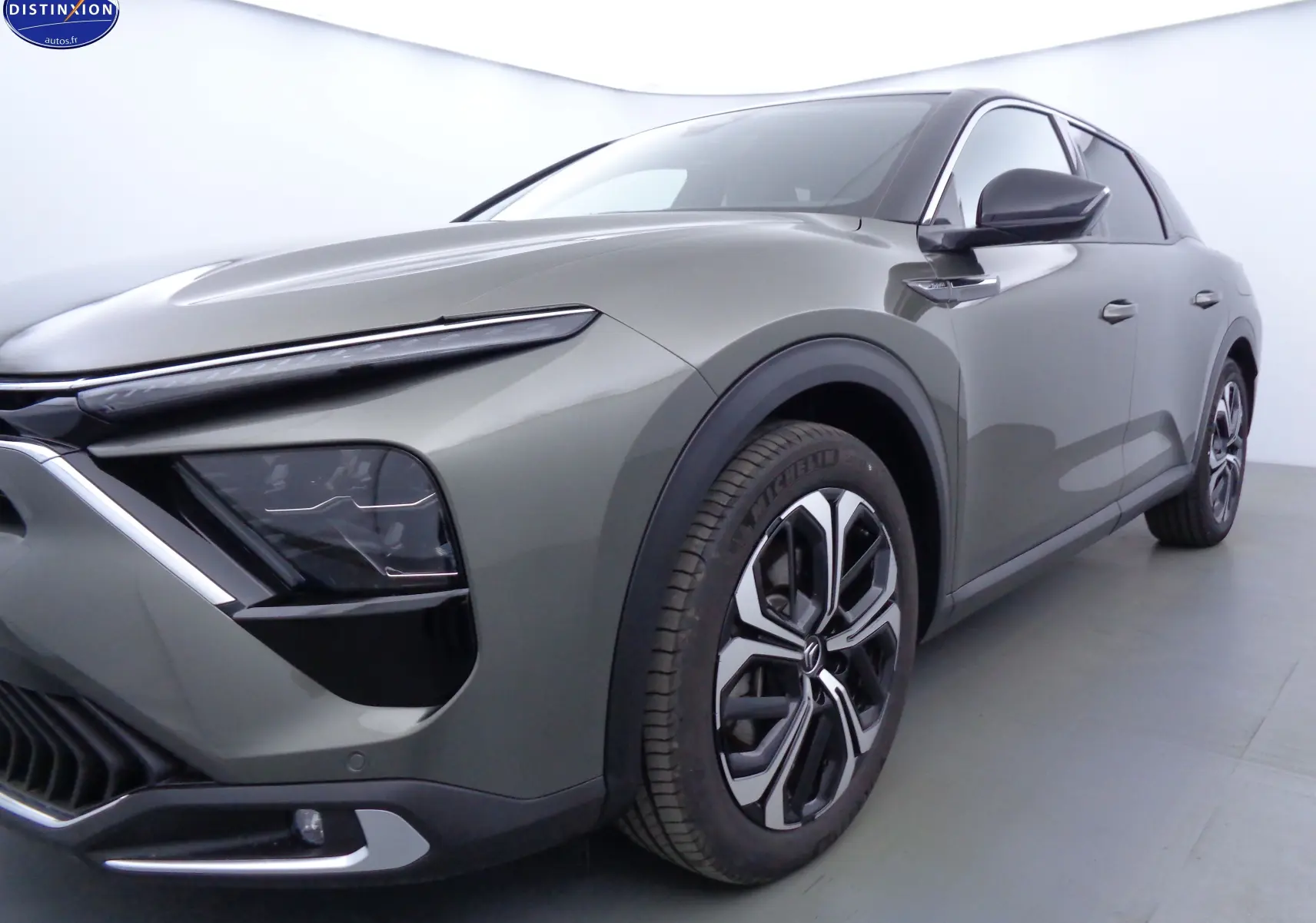 Vue 3/4 avant droit d'une Citroën C5 X hybride rechargeable gris smart avec jantes bi-ton et phares LED distinctifs.