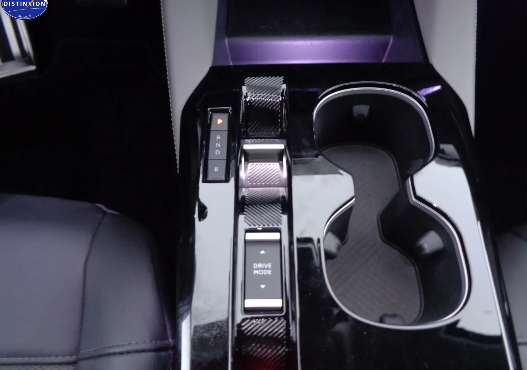 Gros plan sur la console centrale noire brillante du Citroën C5 X Hybrid 225ch avec levier de vitesse et porte-gobelets.