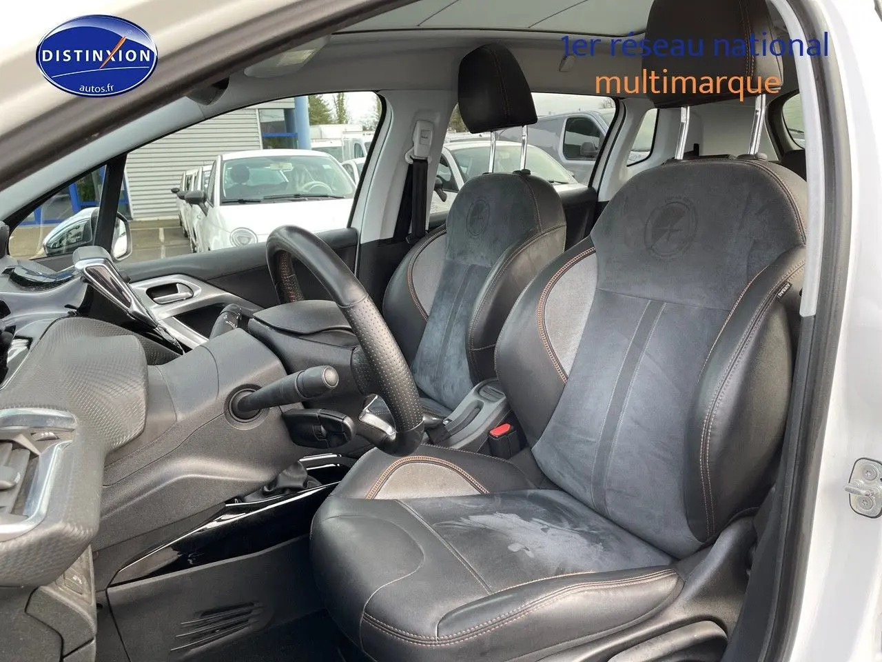 Intérieur du Peugeot 2008 blanc vu côté conducteur, mettant en valeur les sièges en cuir noir avec surpiqûres marron.