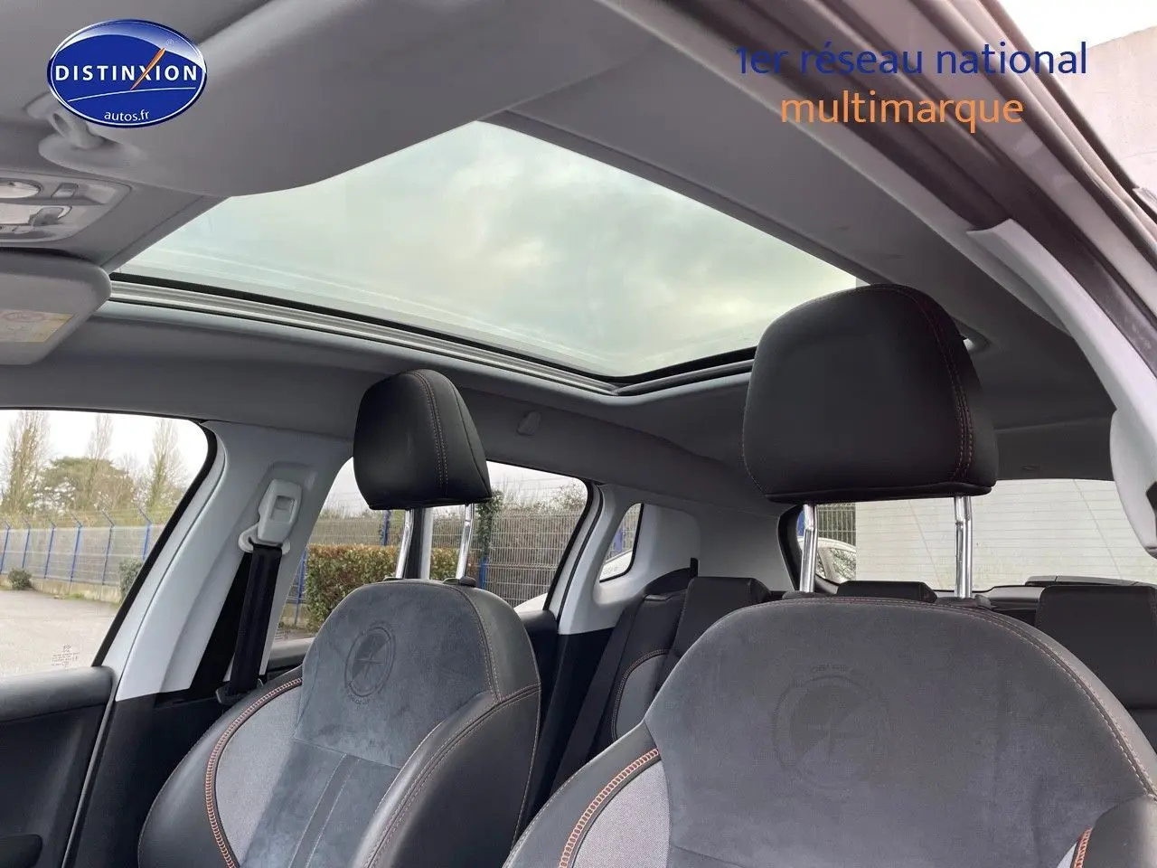 Vue intérieure du Peugeot 2008 blanc 2016, mettant en valeur les sièges avant en cuir noir avec surpiqûres contrastées et toit panoramique.