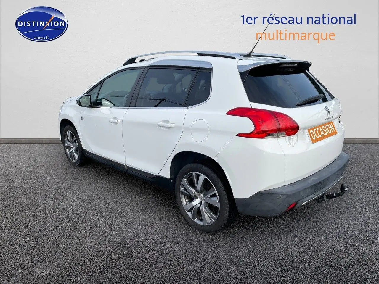 Peugeot 2008 blanc vue 3/4 arrière droit, avec barres de toit et attelage visible sur fond neutre.