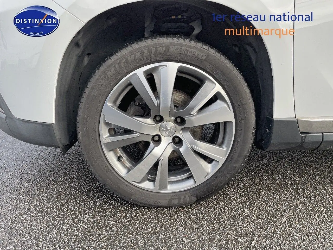 Gros plan sur la roue avant gauche en alliage argenté d'un Peugeot 2008 blanc de 2016.