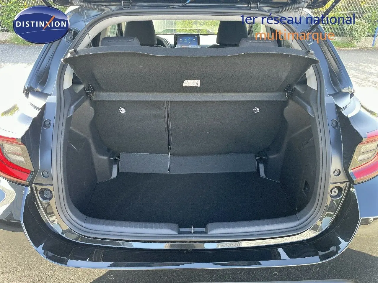 Coffre ouvert vu de l'arrière d'une Toyota Yaris Hybrid 116ch noir métal, intérieur spacieux et banquette relevée.