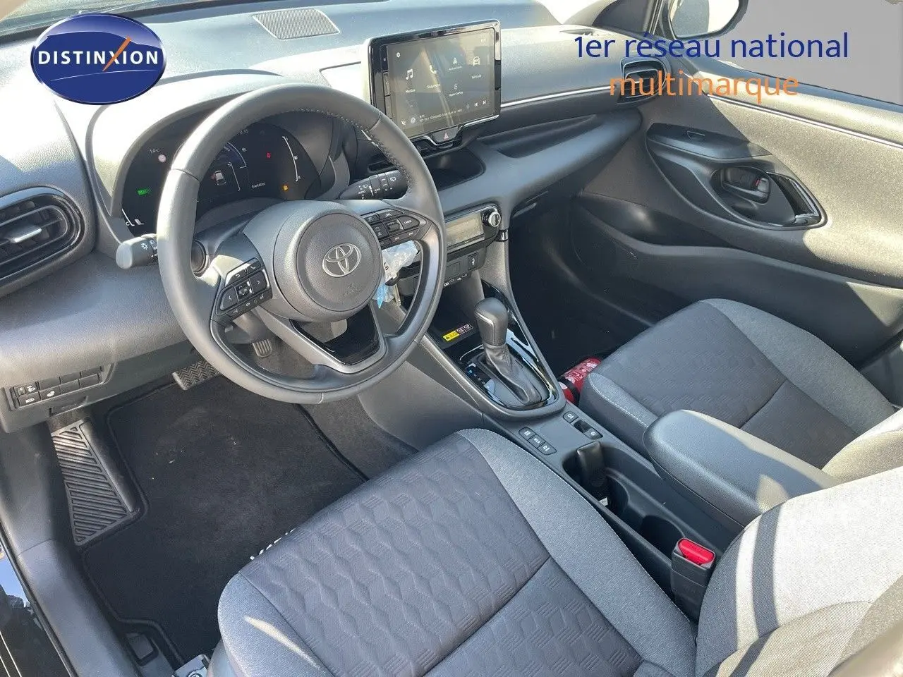 Vue intérieure côté conducteur de la Toyota Yaris Hybrid 2025 avec sièges tissu noir et console centrale moderne.