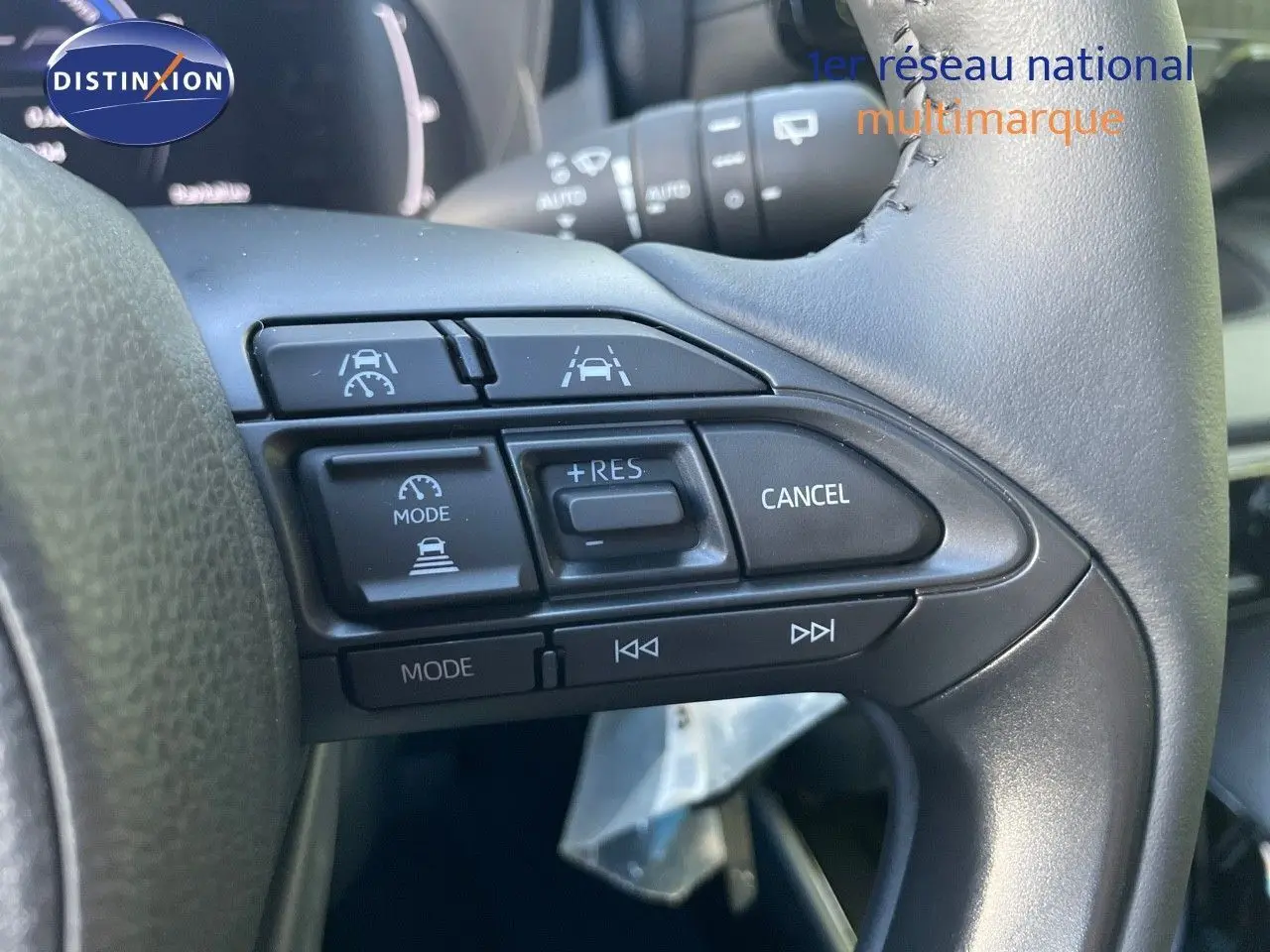 Gros plan sur les commandes au volant droit de la Toyota Yaris Hybrid 2025 avec finition Design noire métal.