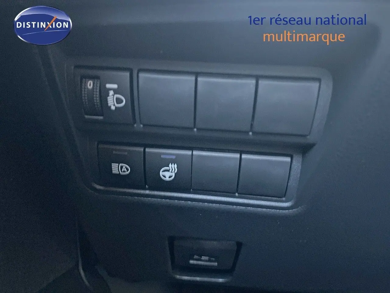 Gros plan sur les commandes de réglage des phares et du volant chauffant dans une Toyota Yaris Hybrid noire 2025.