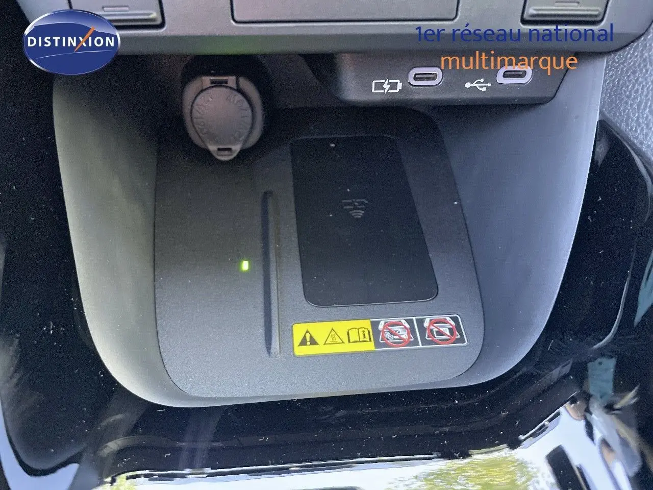Vue rapprochée du chargeur sans fil et des ports USB-C dans l'habitacle d'une Toyota Yaris Hybrid noire 2025.