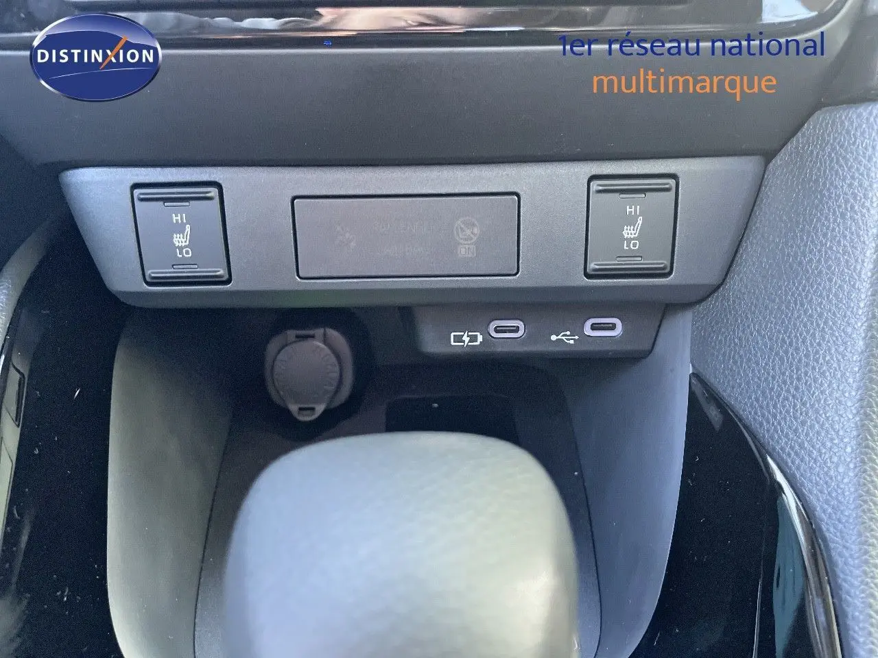 Gros plan sur la console centrale de la Toyota Yaris Hybrid 2025, montrant les commandes des sièges chauffants et ports USB.